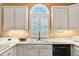 Well-lit kitchen with white cabinets, arched window with shutters and a black dishwasher at 2020 Ridge Gate Drive Dr, Cumming, GA 30041