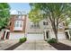 Attractive townhome exterior featuring an attached garage, brick and painted facade with mature trees at 11302 Musette Cir, Alpharetta, GA 30009