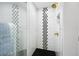 A modern shower with a mosaic accent stripe, glass enclosure and a gold shower head at 1251 Pierce Ave, Smyrna, GA 30080