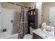 A basic bathroom with a combined bathtub and shower features ample toiletries and a dark wood storage cabinet at 2183 Trinity Grove Ct, Dacula, GA 30019