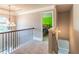 Second floor hallway showcasing a decorative chandelier, wrought iron railing, and doorway view to a bedroom at 2183 Trinity Grove Ct, Dacula, GA 30019