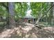 View of brick ranch home in a wooded backyard with large trees providing ample shade and natural landscaping at 1403 Dennis Dr, Decatur, GA 30032