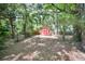 Backyard showcasing a red storage shed surrounded by natural greenery and large trees at 1403 Dennis Dr, Decatur, GA 30032
