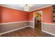 A dining room is shown with dark red paint, laminate floors, and a view into the kitchen at 4137 Donna Ct, Ellenwood, GA 30294
