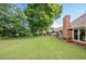 Expansive backyard with lush green lawn, mature trees, and a brick patio area accessible from the house at 535 Brickleberry Ln, Roswell, GA 30075