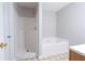 Bathroom featuring a stand-up shower and a soaking tub with neutral tile flooring at 6010 Capitol Knl, Fairburn, GA 30213
