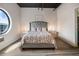Cozy bedroom featuring a tufted headboard, stylish side tables, and a unique circular window at 790 North Ne Ave # 209, Atlanta, GA 30306