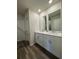 Bathroom featuring double sinks, granite countertops, white cabinets and wood-look tile flooring at 1601 Dosk Ave, Lawrenceville, GA 30044