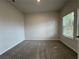 A carpeted bedroom featuring neutral walls, a window for natural light, and a view to the backyard at 1601 Dosk Ave, Lawrenceville, GA 30044