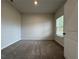 A carpeted bedroom featuring neutral walls, a window for natural light, and a view to the backyard at 1601 Dosk Ave, Lawrenceville, GA 30044