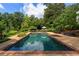 A beautiful rectangular pool with brick trim is surrounded by patio seating and lush landscaping, providing a serene backyard oasis at 3415 Habersham Nw Rd, Atlanta, GA 30305