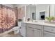 Clean bathroom with gray vanity, fresh green plants, decorative accents, and floral shower curtain at 3711 Wartrace Dr, Atlanta, GA 30331