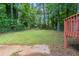 Exterior shot of backyard area with mature trees, a red-stained deck and a partial view of home at 2242 Cherokee Valley Cir, Lithonia, GA 30058