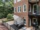 Comfortable outdoor patio with seating, a grill, and manicured shrubs at the back of the brick home at 1292 Lenox Park Ne Blvd, Brookhaven, GA 30319