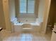 Close-up on a large soaking tub in a bright bathroom with tile floors and white tile surround at 512 Ollas Walk, Mcdonough, GA 30252