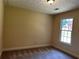 Simple carpeted bedroom with large window offering natural light, neutral walls, and overhead light at 512 Ollas Walk, Mcdonough, GA 30252