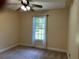 Cozy bedroom with soft carpet, a ceiling fan, and a window overlooking the lush exterior at 512 Ollas Walk, Mcdonough, GA 30252