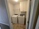 Well-lit laundry room with washer, dryer, overhead cabinets, and tiled floor at 512 Ollas Walk, Mcdonough, GA 30252