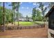 A large backyard with manicured lawn, mature trees, and a black wooden fence surrounding the property at 150 Trinity Farm Dr, Canton, GA 30115