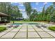 Stunning backyard pool featuring a rectangular design, lounge chairs, and a backdrop of lush greenery and distant building at 150 Trinity Farm Dr, Canton, GA 30115