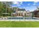 Spacious backyard with a large pool, covered patio, lush lawn, and a beautiful home exterior at 150 Trinity Farm Dr, Canton, GA 30115