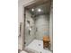 Modern bathroom shower with gray tiled walls, glass door, and wooden bench at 150 Trinity Farm Dr, Canton, GA 30115