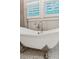 Close-up of a claw foot bathtub with decorative tile and shuttered windows at 150 Trinity Farm Dr, Canton, GA 30115