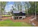 Aerial view of a two story home with an outdoor patio, black siding, and stone work in a wooded area at 150 Trinity Farm Dr, Canton, GA 30115