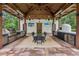 Outdoor kitchen with high-end stainless steel appliances, pizza oven, dining table and wood ceiling at 150 Trinity Farm Dr, Canton, GA 30115