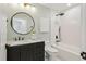 Well-lit bathroom with black fixtures, white tiled shower over tub, and a marble vanity with a round mirror at 1869 Hebron Hills Dr, Tucker, GA 30084