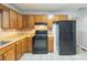 Kitchen features tile flooring, oak cabinets, and black appliances at 2247 Cherokee Valley Dr, Lithonia, GA 30058