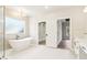 Bright bathroom features a soaking tub under a window, a walk-in closet, and a vanity with modern fixtures at 3735 Tamiami Trl, Cumming, GA 30041