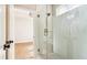 Bright bathroom features a glass-enclosed shower, with brass hardware, next to doorway with black hardware at 3735 Tamiami Trl, Cumming, GA 30041