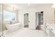 Bright bathroom featuring a standalone tub under a window, adjacent to a walk-in closet at 3735 Tamiami Trl, Cumming, GA 30041