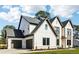 Modern two-story home with a three-car garage, a mix of white siding and brick, and a manicured lawn at 3735 Tamiami Trl, Cumming, GA 30041