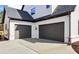 Two-car garage with dark gray doors, a connecting driveway, and white board and batten siding at 3735 Tamiami Trl, Cumming, GA 30041