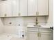 Functional laundry room with white cabinets, gold hardware, and convenient sink area at 3735 Tamiami Trl, Cumming, GA 30041