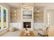 Well-lit living room with a fireplace, built-in cabinets and shelves, and large windows with green views at 3735 Tamiami Trl, Cumming, GA 30041