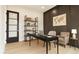 Contemporary office featuring a desk, chairs, and shelving, with a glass door, wood floors, and warm decor at 3735 Tamiami Trl, Cumming, GA 30041