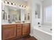 Bathroom with double vanity, soaking tub, dark wood floors, and white walls at 6160 Oriole Ln, Cumming, GA 30028