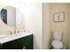 Bathroom features a gold faucet and round mirror with a white toilet and small black storage unit at 300 Saddle Creek Ln, Roswell, GA 30076