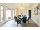 Elegant dining room with modern chandelier, bay window, wood floors, and a round glass table at 300 Saddle Creek Ln, Roswell, GA 30076
