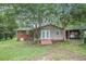 A spacious backyard showcasing a home with double doors leading to a wooden deck and mature trees at 734 Meadowlark Dr, Villa Rica, GA 30180