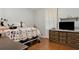Cozy bedroom featuring hardwood floors, a plush quilt, a dresser, and a shelf for decorative items at 136 Pine St, Covington, GA 30014