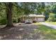 Quaint ranch home featuring a metal roof, white-railed front porch, and an attached garage, surrounded by trees at 136 Pine St, Covington, GA 30014