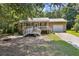 Charming ranch-style home with a metal roof, front porch, and attached garage, nestled amongst lush greenery at 136 Pine St, Covington, GA 30014