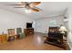 Well-lit living room featuring hardwood floors, a ceiling fan, fireplace, and a television; perfect for relaxation at 136 Pine St, Covington, GA 30014