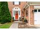 Close-up of the red front door with decorative wreath, set within a classic brick facade at 1767 Tidewell Trce, Lawrenceville, GA 30043