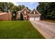 Classic brick home with a manicured lawn, a two-car garage, and mature trees offering shade at 1767 Tidewell Trce, Lawrenceville, GA 30043