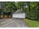 Two-car detached garage with white doors and a concrete driveway surrounded by lush trees and greenery at 2177 Mauldin Nw St, Atlanta, GA 30318